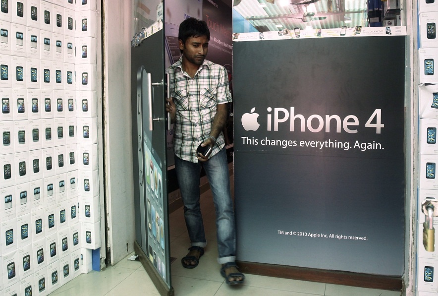 Một người dùng bước ra khỏi cửa hàng bán lẻ - nơi trưng bày quảng cáo iPhone 4 ngay tại mặt tiền ở Mumbai, Ấn Độ.