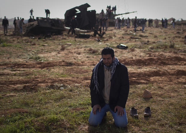 Một người đàn ông Libya quỳ cầu nguyện phía trước một chiếc xe tăng bị phá hủy ở ngoại ô Benghazi, Libya. AP