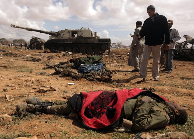 Thi thể một binh sĩ da màu trong hàng ngũ quân đội trung thành với nhà lãnh đạo Gaddafi bị tiêu diệt ở al-Wayfiyah. Những người tò mò đang chụp ảnh xác chết bằng điện thoại di động. Ảnh: AFP