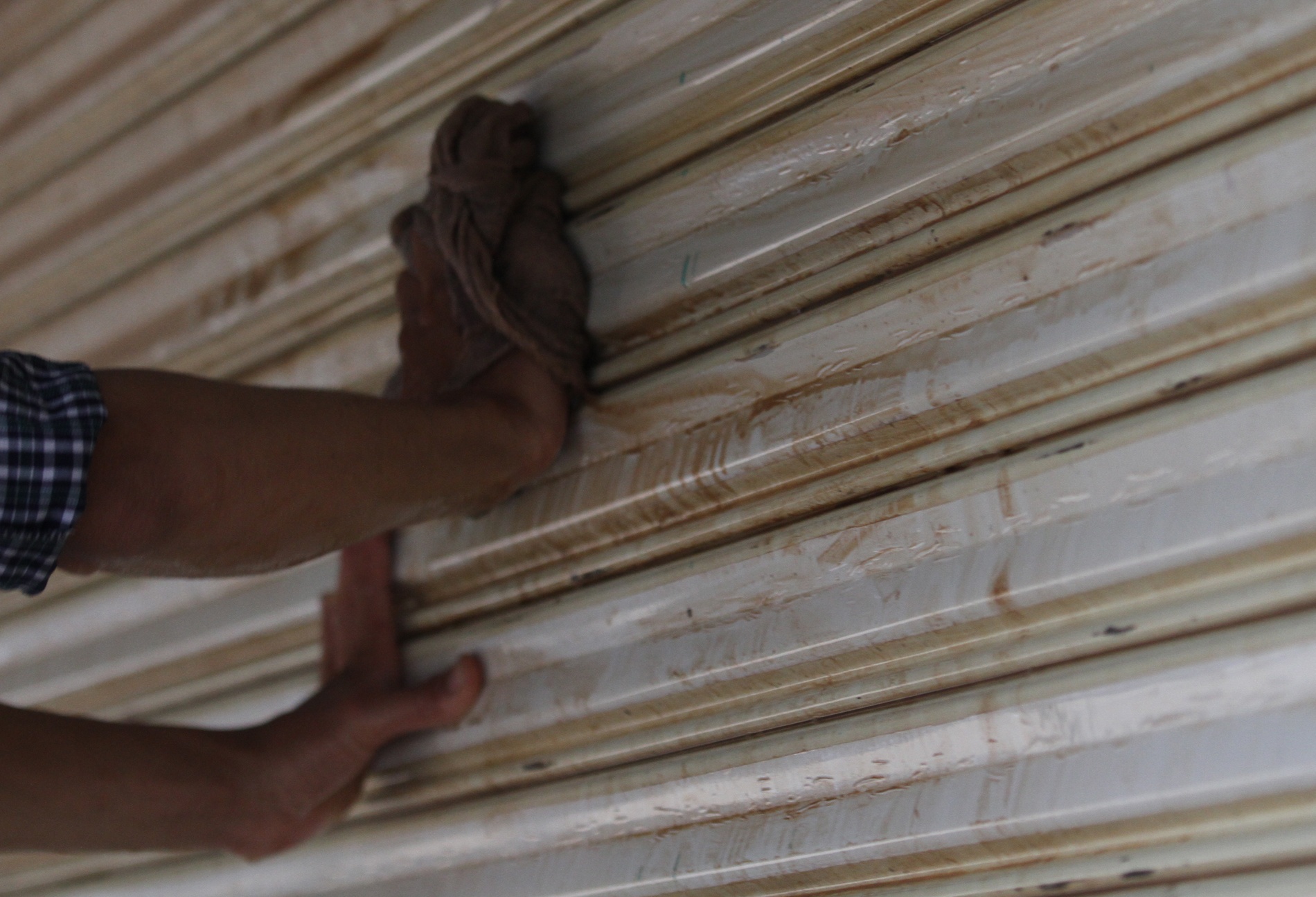 8.	Nước ngập sâu, bùn đất bám nhiều trên các bức tường, cánh cửa. Trong ảnh là chủ sạp hàng thịt chó Chiến Lập cặm cụi tỉ mẩn lau chùi.