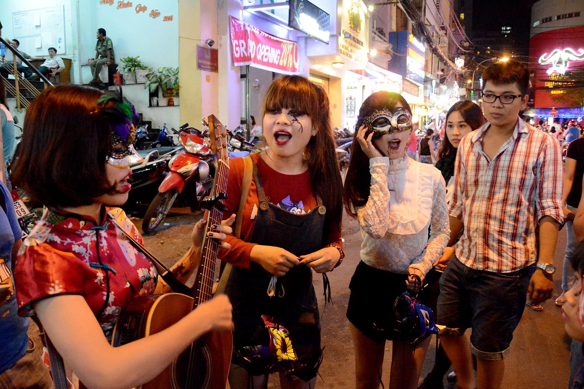 3 cô gái sinh viên của Trường Đại học Hùng Vương cầm đàn ca hát thu hút sự chú ý để bán mặt nạ handmade do chính tay họ làm.