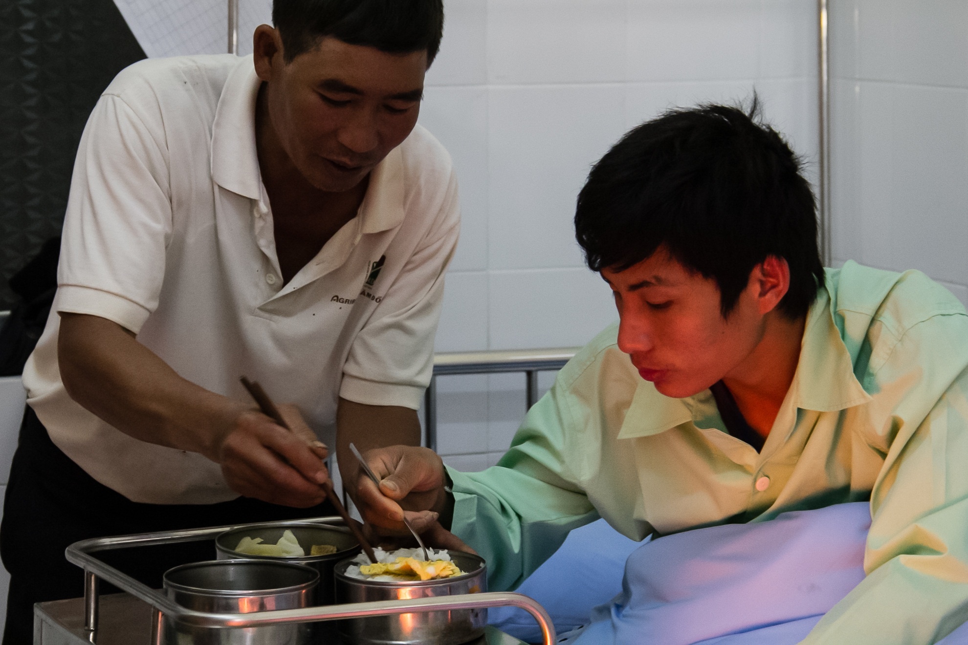 Được sự giúp đỡ của gia đình, Quang đã ăn ngồi dậy để ăn cơm.