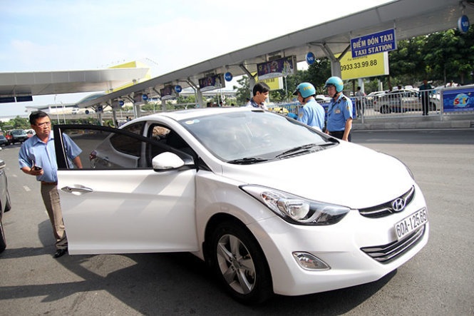 Thanh tra giao thông kiểm tra một chiếc xe chở khách qua dịch vụ Uber tại sân bay Tân Sơn Nhất (TP.HCM).