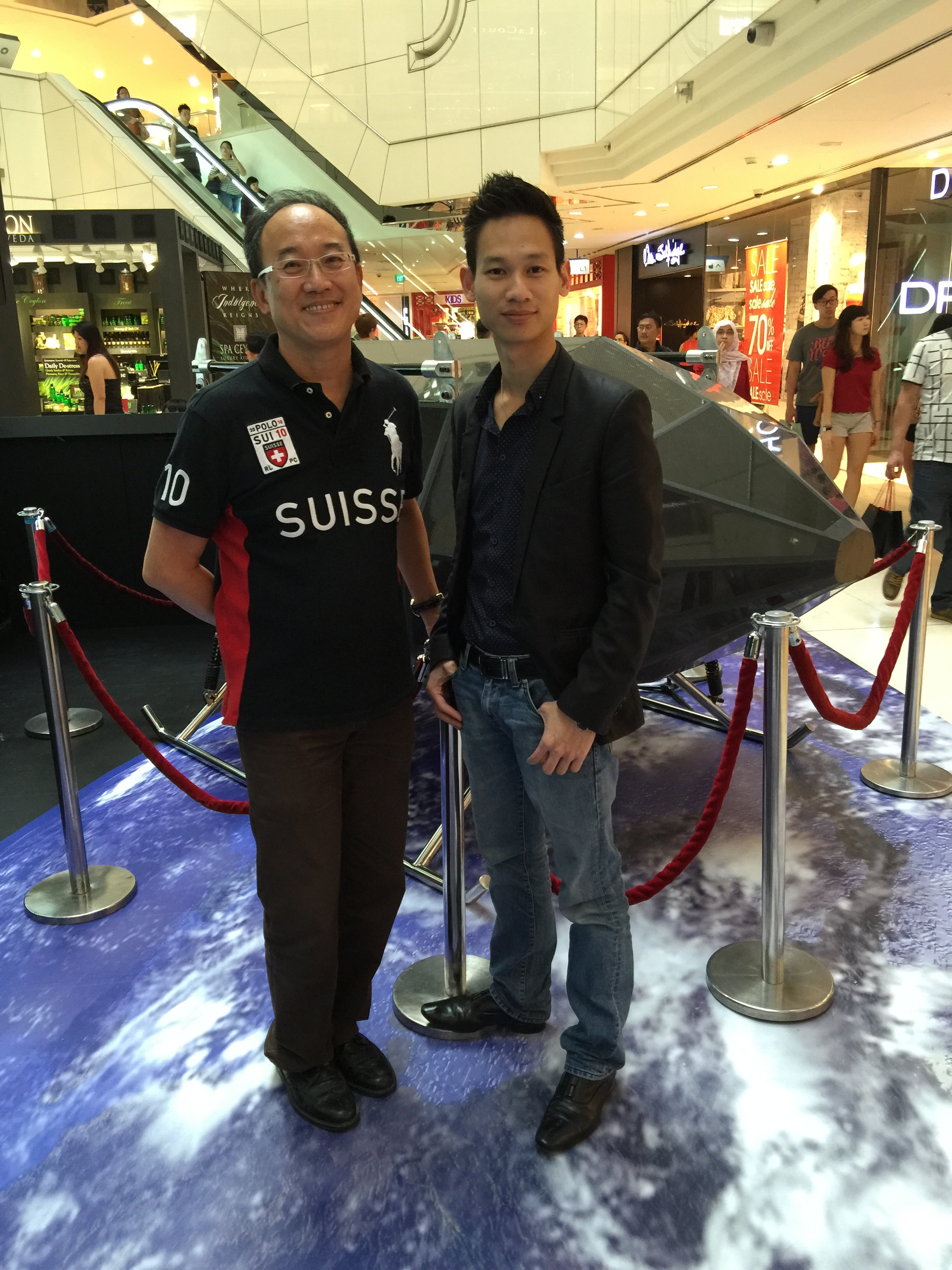 Anh Phạm Gia Vinh (bên phải) bên thiết bị của mình tại Singapore.
