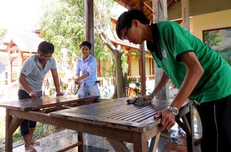 Tình nguyện viên Câu lạc bộ 25 tham gia chà rửa bàn ghế phục vụ bữa ăn cho thí sinh.