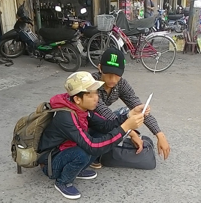 Hai anh em N.T.H. và N.V.H. (quê Đắk Lắk) thất thần ngồi xem lại bản hợp đồng khoán việc bốc xếp sau khi biết mình bị lừa mất tiền - Ảnh: Quang Phương