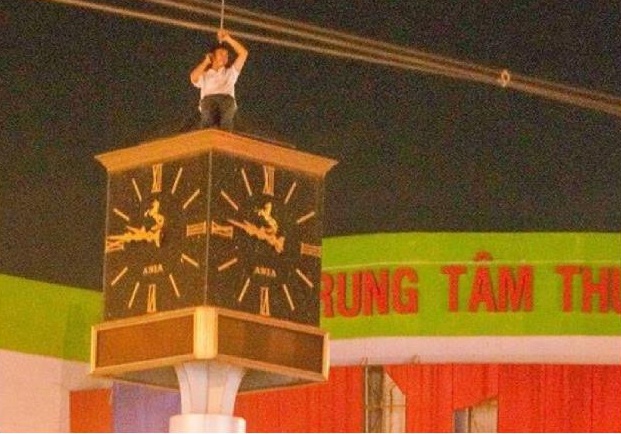 Nam sinh treo len thap dong ho giua giao lo tu tu hinh anh