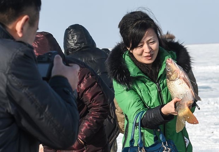 Một du khách thích thú với con cá tươi mới bắt được từ dưới lòng hồ băng.