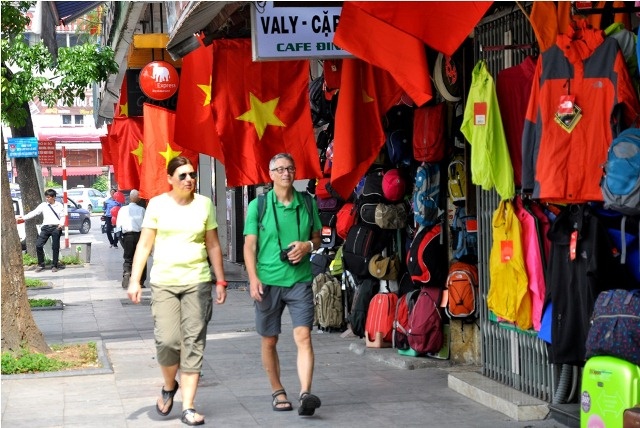 Du khách nước ngoài dạo bước trên con phố Hàng Bông ngập màu cờ đỏ.