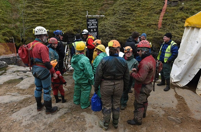 Những người thám hiểm mặc đồ bảo hộ chuẩn bị đu xuống hang.