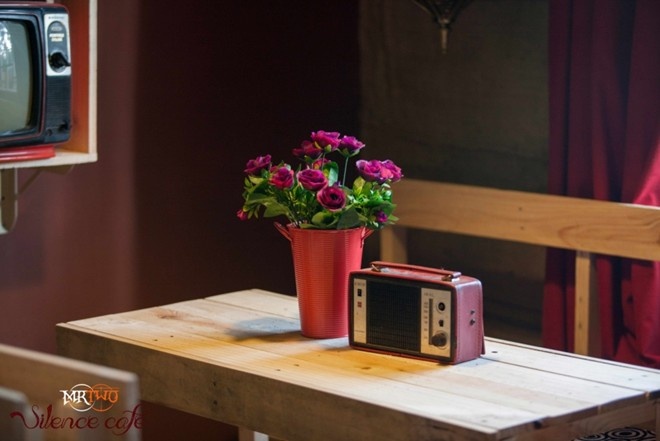   Không gian gợi nhớ bức tranh cuộc sống thanh bình của thập niên 90 đầy hoài niệm khiến tâm hồn các cặp yêu nhau như càng gắn kết hơn.  Tọa lạc tại số 1192 đường Trường Sa, Phường 13, Q.Phú Nhuận,  Silence Café là sự gợi ý không tồi cho những ai tìm kiếm một không gian lãng mạn cần thiết cho lời tỏ tình hay cầu hôn bất ngờ. Silence, chốn lãng mạn cho những con tim yêu  Ấn tượng đầu tiên về Silence của bạn có thể gói gọn trong cụm từ “không có gì nổi bật” – từ hình thức đến nội dung. Song nếu chịu khó làm khách một lần, bạn sẽ ghiền cái không gian tưởng như không có gì mới lạ ấy.  Quán không rộng, chỉ chứa được khoảng 50 người, song dưới bàn tay tài hoa của người thiết kế, quán như “phình” ra nhiều, với nhiều góc dành cho các đối tượng khác nhau. Đó có thể là một nhóm bạn với những góc ngồi thoải mái để trò chuyện, chơi trò chơi. Là đôi bạn thân cần một góc yên tĩnh, nhấm nháp món nước yêu thích, thả hồn theo tiếng nhạc. Một người khách mệt mỏi trong góc vắng, nhắm mắt, thả trôi mọi vướng mắc, lo lắng.