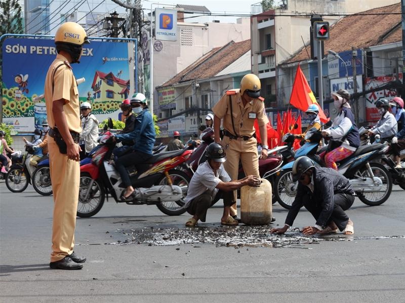 Hai CSGT doi nang giup dan gom ca do ra duong hinh anh