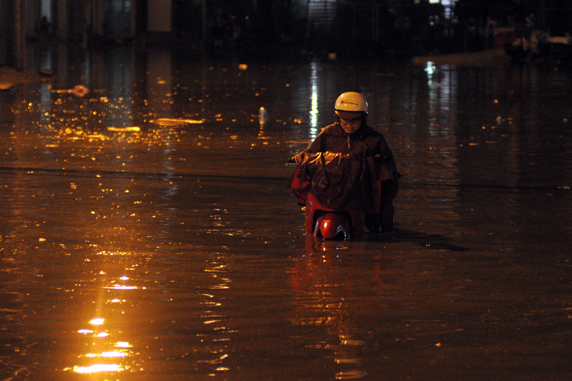 Một người phụ nữ dắt xe đi trong nước ngập đến ngang đầu chiếc xe tay ga, khoảng gần 1 mét. Ảnh: Nguyễn Quang.