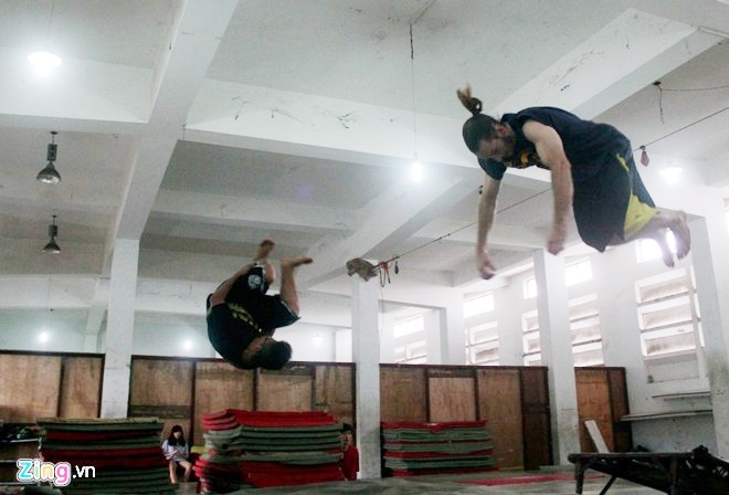 Vy Thành, người đã có 7 năm tập môn thể thao mạo hiểm này chia sẻ, các bạn trong nhóm chủ yếu tập các động tác được gọi là Tricking (dậm nhảy từ giá dây cao su bay lên lộn vòng và tiếp đất xuống đệm), Backflin (xoay người và bật nhảy từ dưới đất lên không trung), nhảy vượt địa hình và nhảy các động tác tự do. Trong ảnh, hai thành viên nhảy động tác Tricking, bay người lên cao và lộn nhiều vòng.