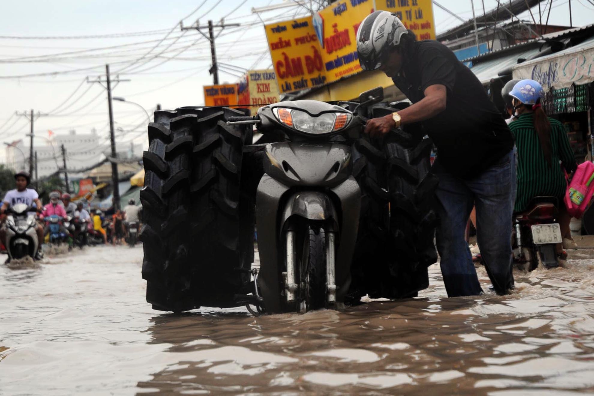 Người đàn ông chở hàng hóa vật lộn giữa dòng nước ngập.