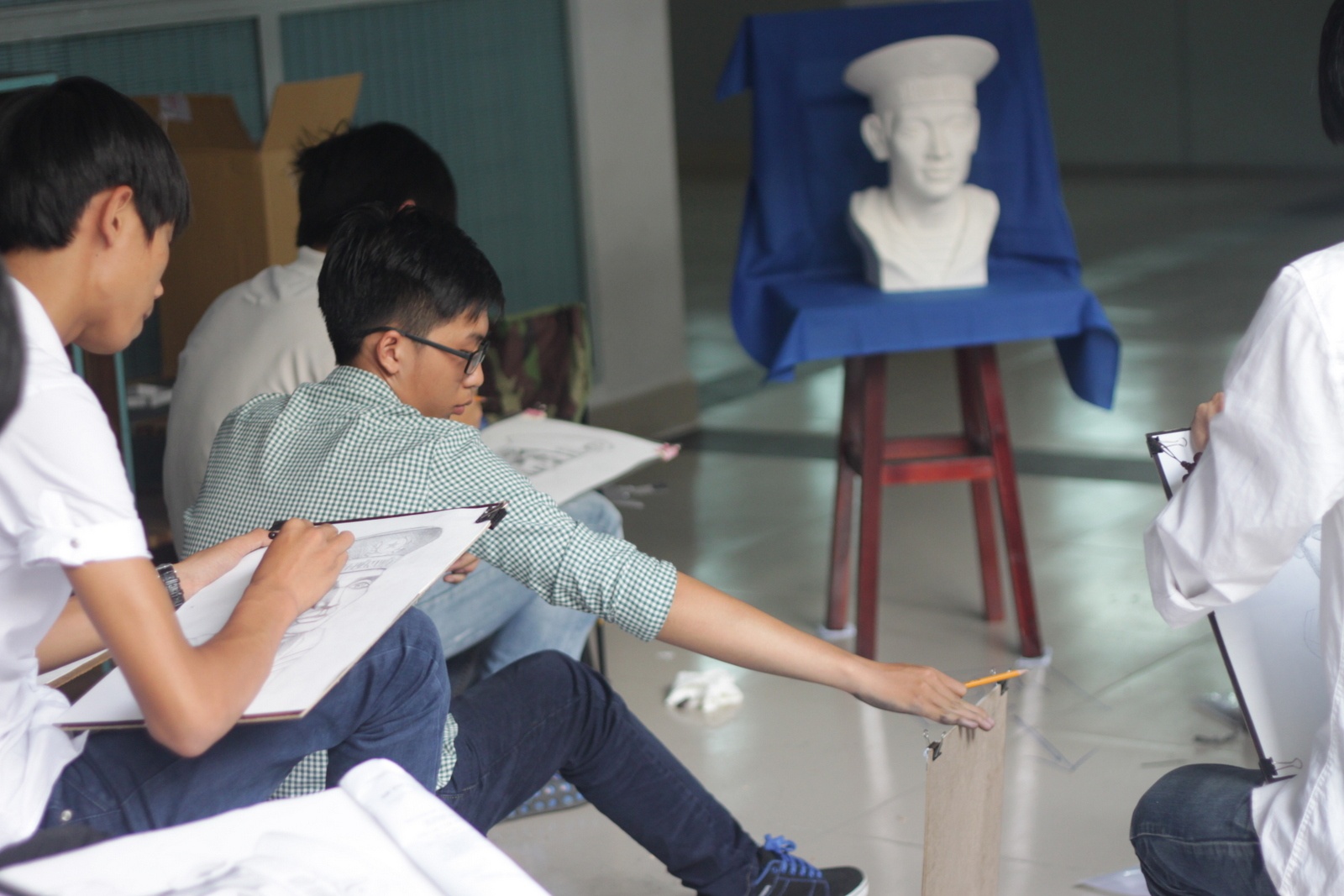 Thí sinh Nguyễn Trường Phú (18 tuổi, H.Cái Bè, Tiền Giang) đối chiếu lại hình vẽ của mình so với mẫu. Theo Phú, bài thi của cậu khá tốt, nhưng phần vễ dòng chữ trên mũ lại không như ý vì quá nhiều chi tiết.