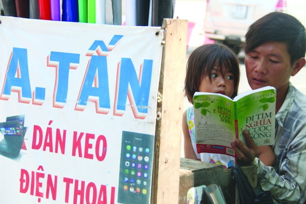 Người cha làm nghề dán điện thoại, laptop. Ảnh không ghi rõ tên người chụp cũng như nguồn.