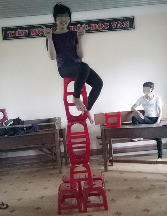 Hình ảnh cô gái táo bạo ngồi trên chồng ghế cao ngất.