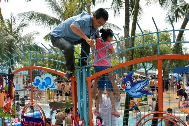 Hình ảnh bố bế con qua hàng rào sắt nhọn.