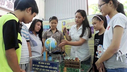 Trần Đào Hải Ngọc (áo trắng) với mô hình sa bàn mô tả quá trình nước biển dâng gây ngập lụt các vùng ven biển.
