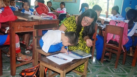 Cô giáo Sành đang giúp em Tài viết chữ.