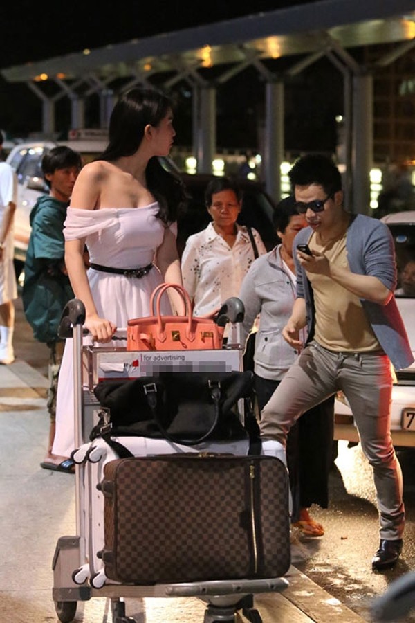 Chiếc đầm midi trễ vai cùng đôi giày cao gót của Ngọc Trinh hẳn rất hợp với những sự kiện trong ngành giải trí. Nhưng khi được đặt trong bối cảnh sân bay tấp nập và hối hả, trang phục này trở nên lệch tông hoàn toàn.