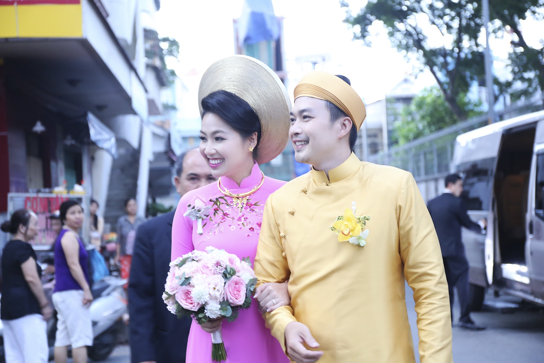 Lê Khánh và Tuấn Khải không quên chào hỏi bà con lối xóm khi tiến về phía đoàn ô-tô đợi sẵn.