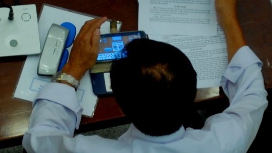 Vị đại biểu chăm chú vào màn hình điện thoại