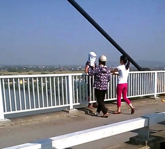 2 nữ cảnh sát mặc thường phục tiếp cận người phụ nữ định nhảy cầu (ảnh cắt ra từ clip do người dân cung cấp) để thuyết phục, động viên
