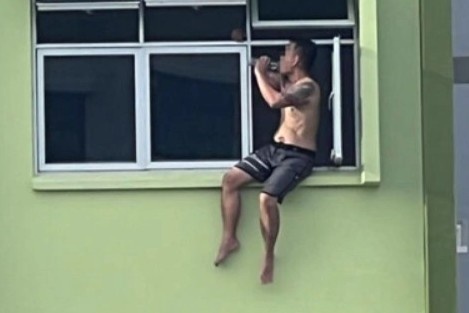 Nguoi dan ong Singapore ngoi uong ruou o be cua so tang 11 de tron no hinh anh