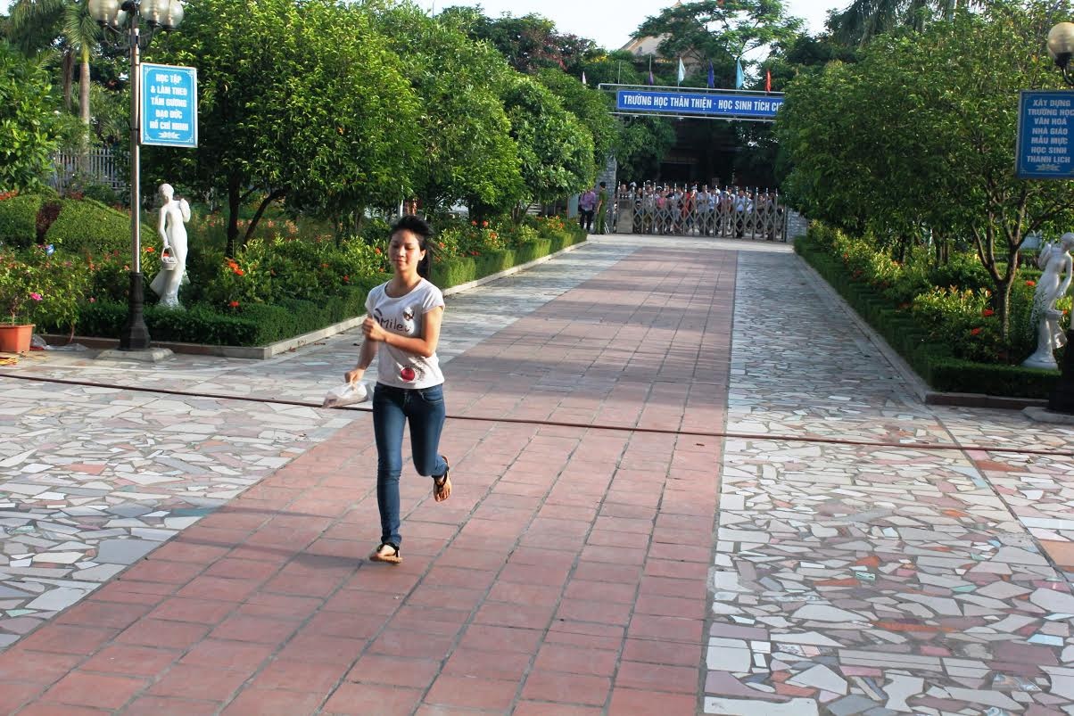 Cổng trường đã đóng nhưng chưa đến thời gian làm bài nên thí sinh vẫn được vào. Cô gái này thi tại Vinh, lao nhanh vào trường trong buổi thi đầu tiên. 