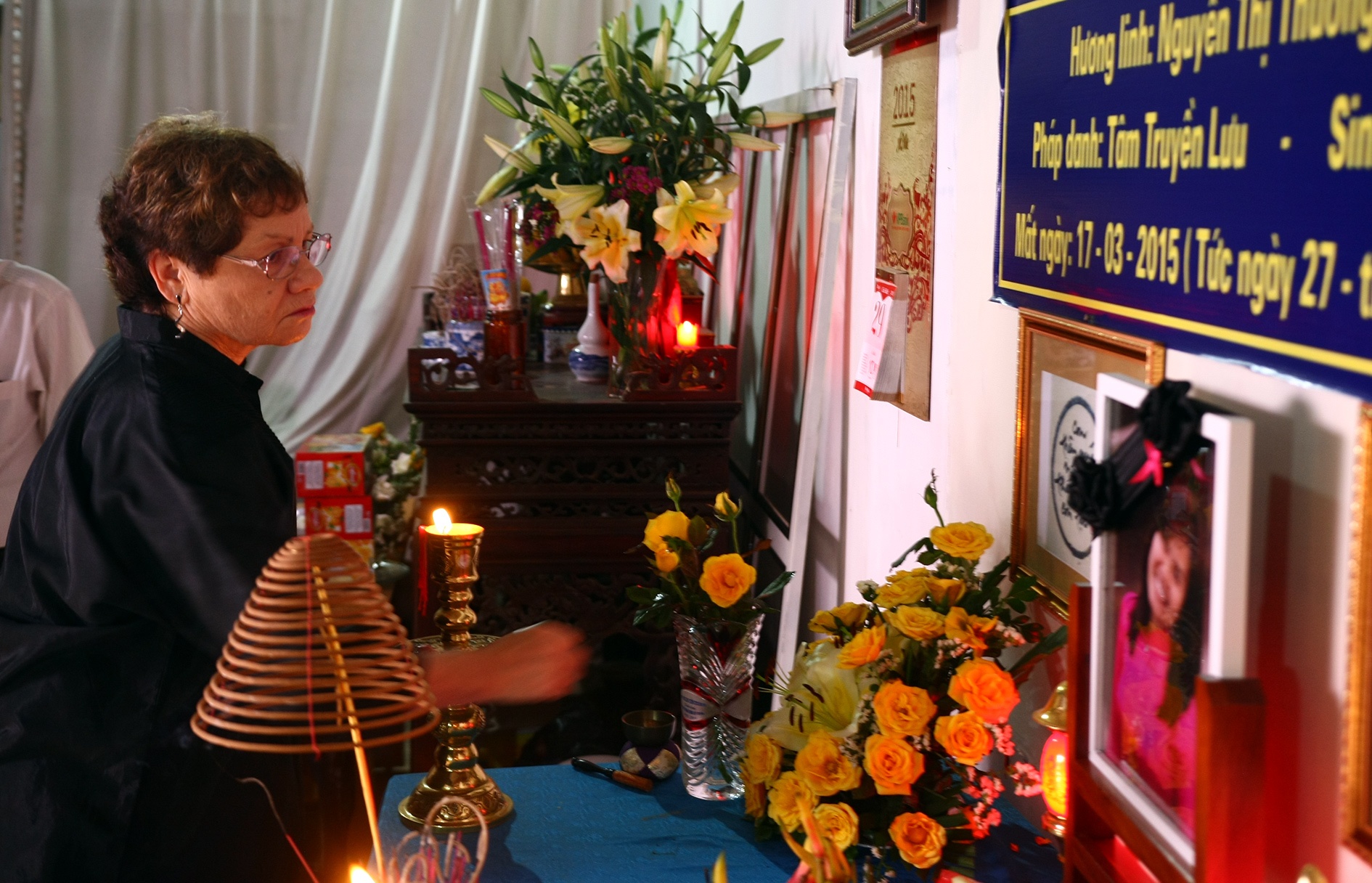 Mẹ chồng đặt hoa trên bàn thờ con dâu quá cố.