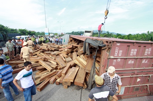 Lat xe cho go, 2 phu nu ngoi trong cabin chet tai cho hinh anh