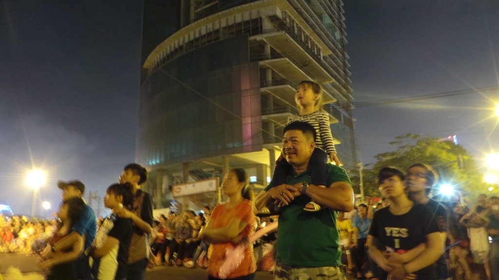 Nhiều em bé được cha cõng trên vai để xem.