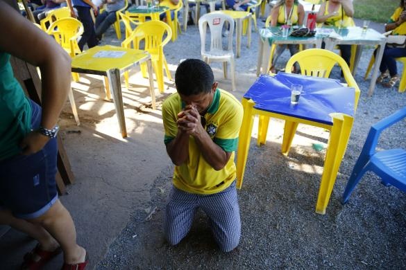 Một fan Brazil đang cầu nguyện trong lúc xem trận đấu giữa Brazil với Chile - Ảnh: Reuters
