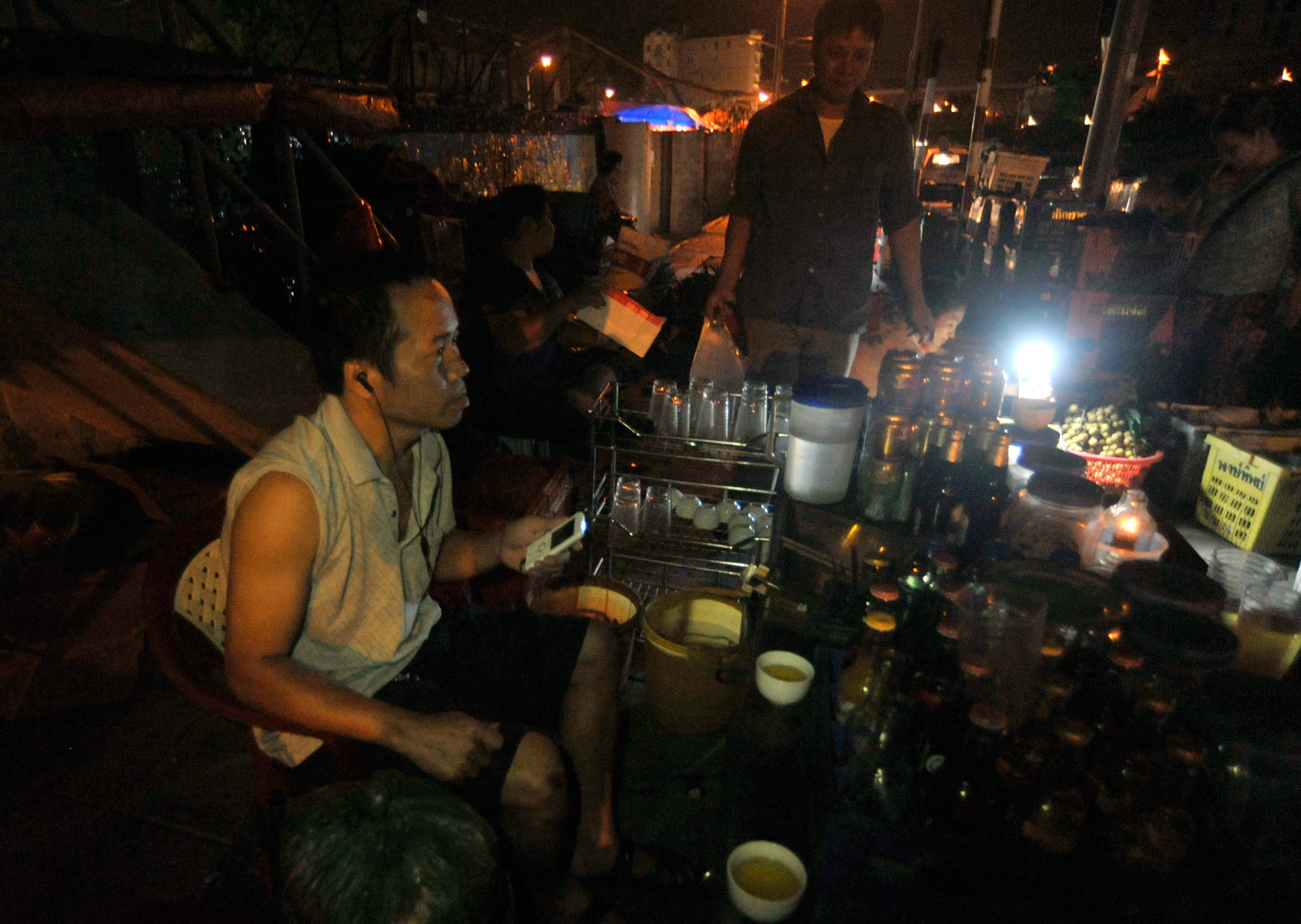 Phía ngoài chợ, a Cảnh bán nước chè cho đám cửu vạn và lái xe thì đành phải nghe radio của điện thoại để biết diễn biến trận đấu