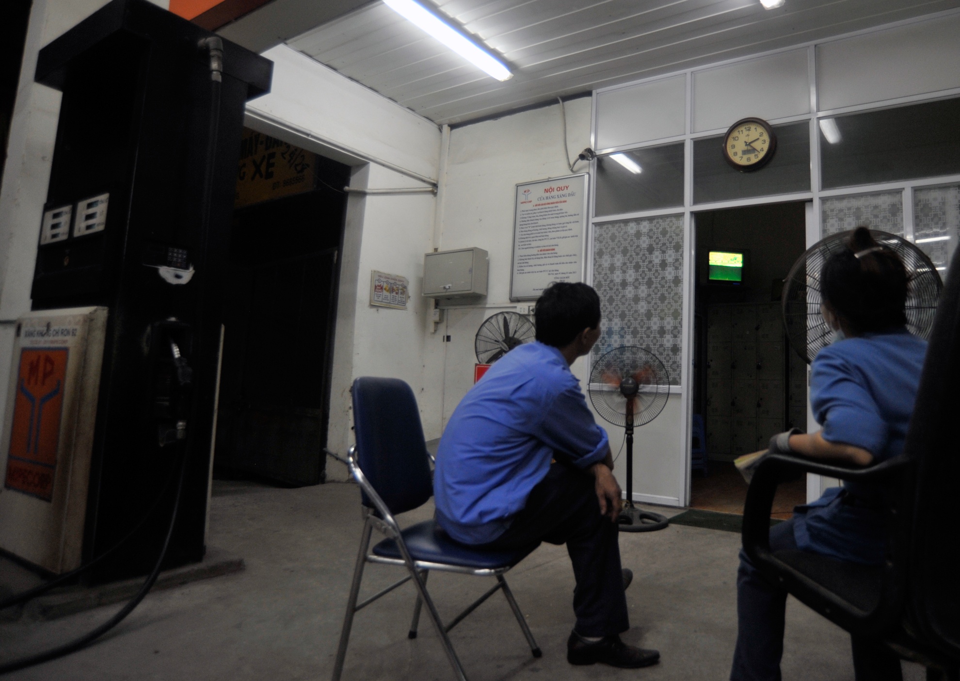 Cây xăng quân đội tại đường Giải Phóng, anh Bình và chị Tuyến tranh thủ khi không có xe vào đổ xăng cũng hướng mắt lên chiếc ti vi nhỏ trong phòng để theo dõi trận đấu