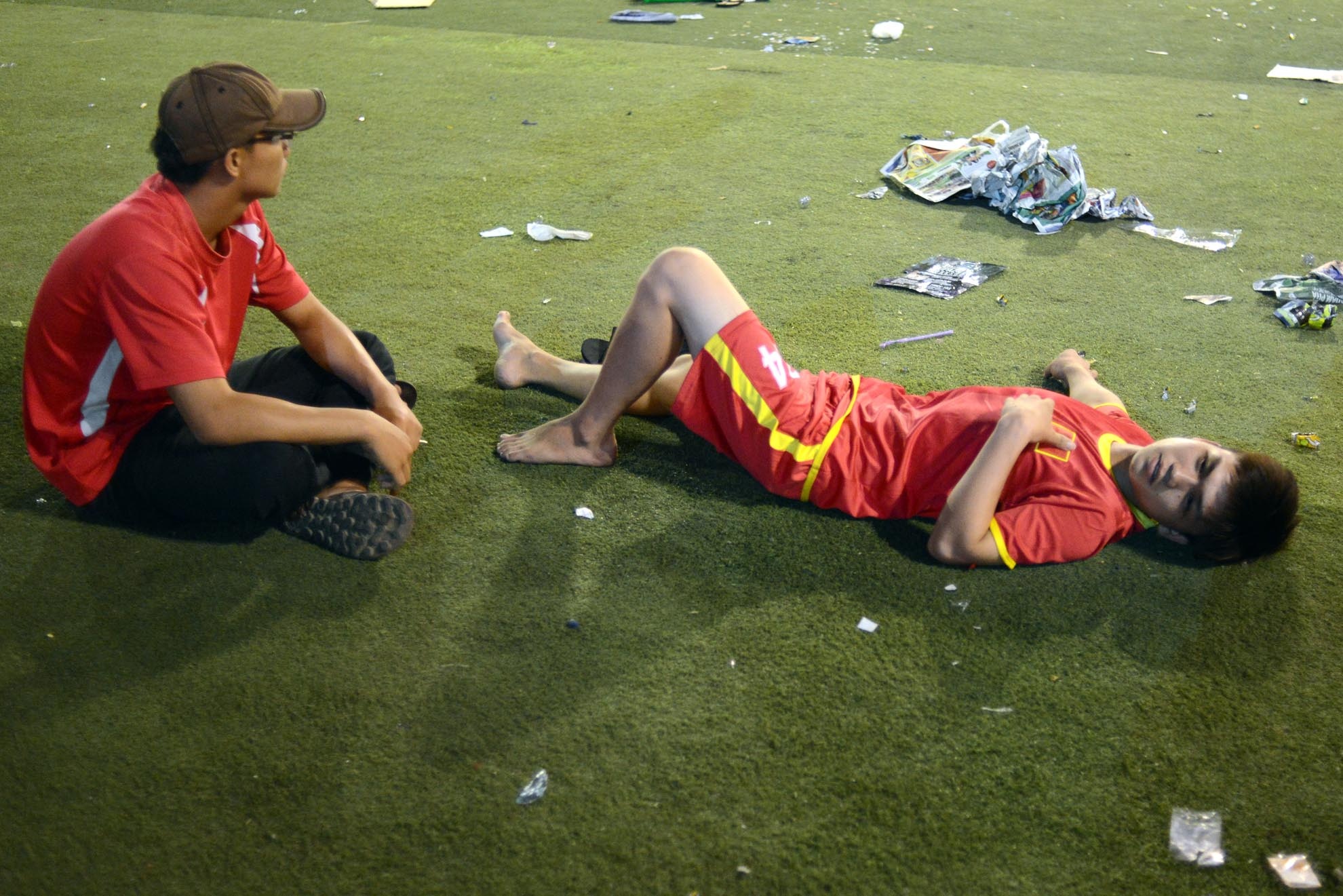 CĐV nam nằm dài trên sân một mình sau trận đấu.