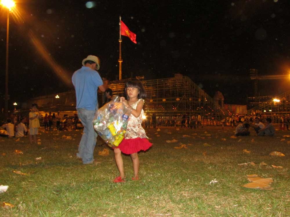 Một bé gái nhặt vỏ chai nhựa tại quảng trường Ngọ Môn sau buổi khai mạc Festival Huế 2014