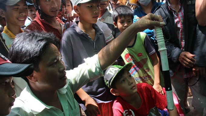 Một người dân cầm dùi cui của công an tại hiện trường.