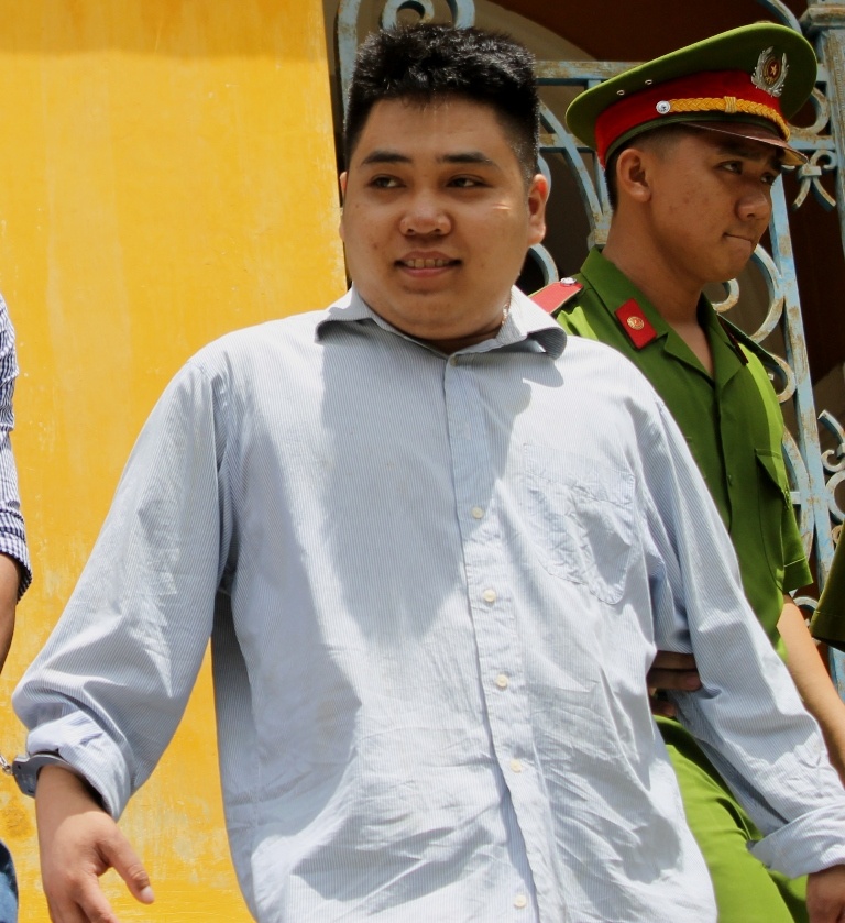 Tân mỉm cười chào người thân khi bị dẫn giải sau phiên tòa.