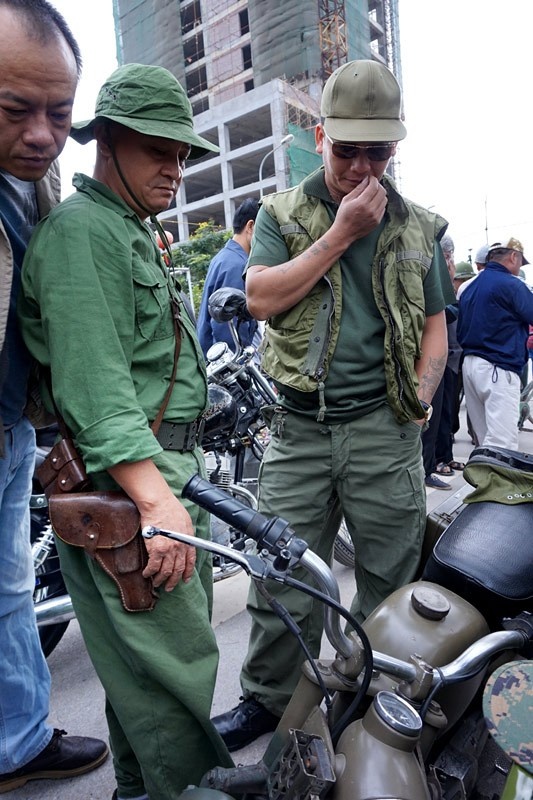 Chủ sạp hàng bán đồ quân dụng trong trang phục giải phóng quân thời chiến tranh chống Mỹ đang 