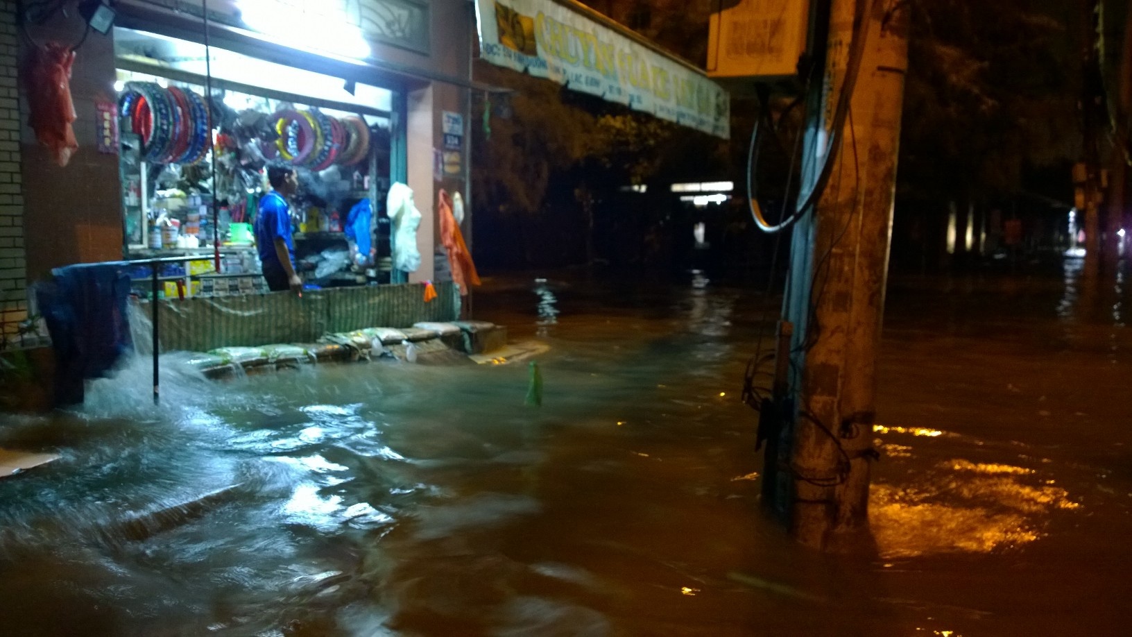 Sóng đánh vào tiệm phụ tùng xe máy bên đường. Ảnh: K.T.