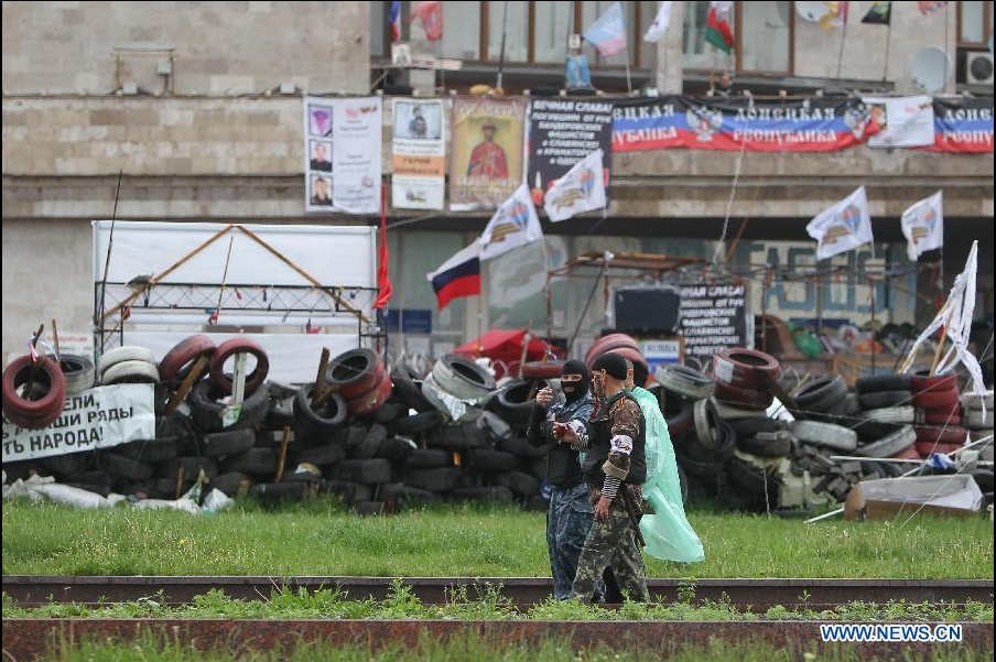 một số thành viên của lực lượng ly khai thân Nga đi dạo bên ngoài một toà nhà chính quyền tại thành phố Donetsk thuộc Ukraina