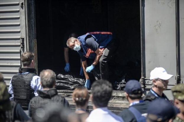 Các quan sát viên từ Tổ chức An ninh và Hợp tác châu Âu kiểm tra những túi đựng thi thể nạn nhân trước khi tàu hỏa rời trạm ở Torez.. Trước khi nhân viên Cơ quan khẩn cấp Ukraina và phiến quân di chuyển khỏi hiện trường, các thi thể này đã nằm phơi dưới nắng mặt trời khoảng ba ngày. Ảnh: MSN