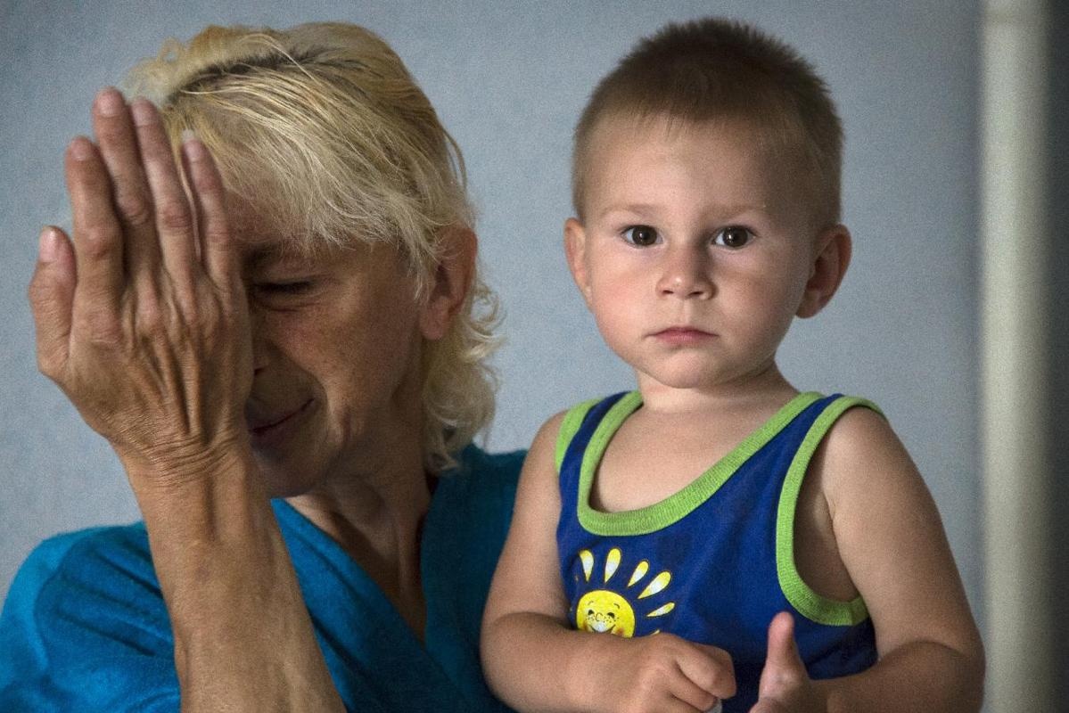 Refugee Svetlana Panteleyeva cries as she holds her grandson Egor, in a dormitory, after being displaced due to shelling, in the city of Donetsk, eastern Ukraine Sunday, July 13, 2014. (AP Photo/Dmitry Lovetsky)