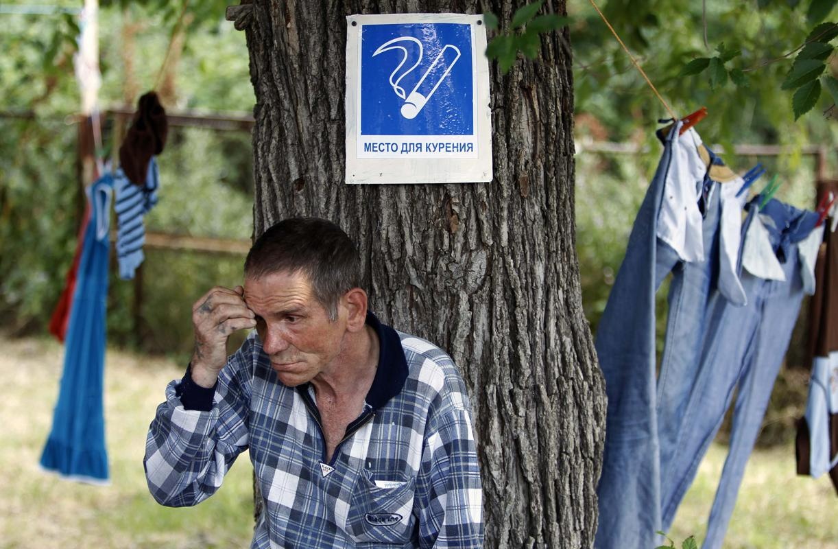 A refugee from eastern Ukraine sits under a tree in a school yard, which is currently being used as a temporary shelter, in the village of Grigoropolisskaya, northwest of the Russian southern city of Stavropol, June 25, 2014. (REUTERS/Eduard Korniyenko)