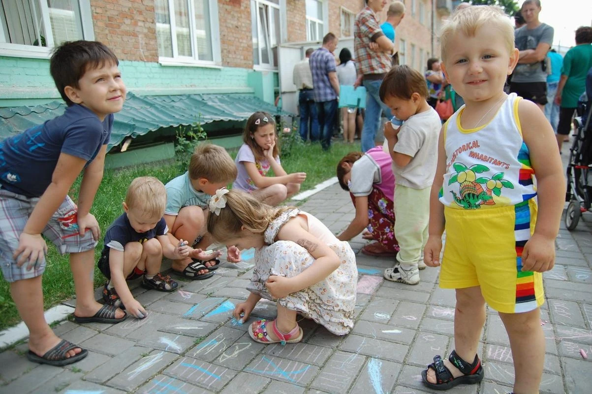 People gather outside an office of the Russian federal migration service, with children seen playing in the foreground, in Belgorod, June 9, 2014. (REUTERS/Vladimir Kornev)