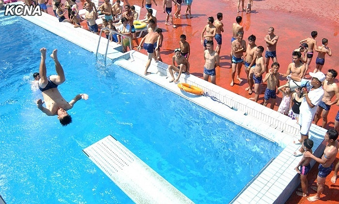 Nhiều người đứng xung quanh bể bơi để chứng kiến màn nhào lộn của một thanh niên.