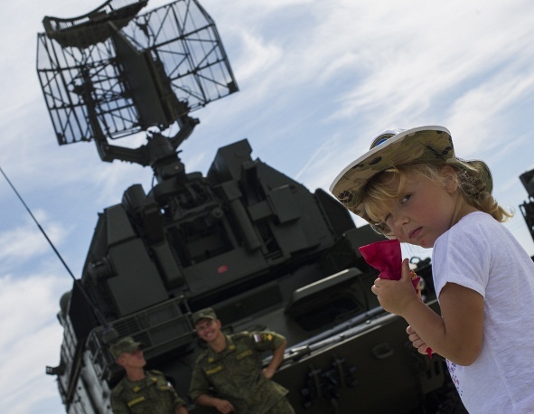 Một bé gái Nga chụp ảnh gần tên lửa Tor-M1 tại cuộc triển lãm. Tor-M1 là hệ thống tên lửa phòng không đất đối không tự hành có tính năng tiên tiến của Nga. Nó thể tiêu diệt các mục tiêu là máy bay, trực thăng, tên lửa hành trình, vũ khí điều khiển chính xác, máy bay không người lái và tên lửa đường đạn.